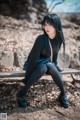 A woman sitting on a bench in the woods.