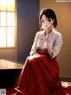 A woman in a red kimono sitting on a table.