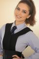 A woman in a blue shirt and black vest posing for a picture.