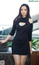 A woman in a black dress standing next to a typewriter.