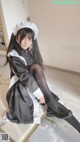 A woman in a maid outfit sitting on a bench.