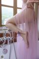 A woman in a pink dress sitting in a bathtub.