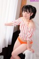 A woman in an orange and white striped top and orange panties.