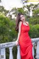 A woman in a red dress leaning on a railing.