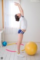 A woman in a white shirt and blue shorts doing a yoga pose.