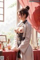 A woman in traditional attire stands by a table with decorative items.